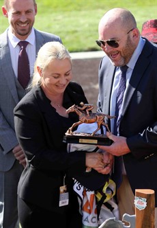 Olivia Cairns receives the winning trainer's trophy from Peter Moody