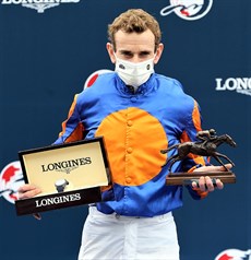 Winning jockey Ryan Moore poses for a photo with a bronze horse and jockey statuette and a LONGINES Conquest V.H.P. Collection watch ... after Mogul had taken out the Longines Hong Kong Vase (see below)